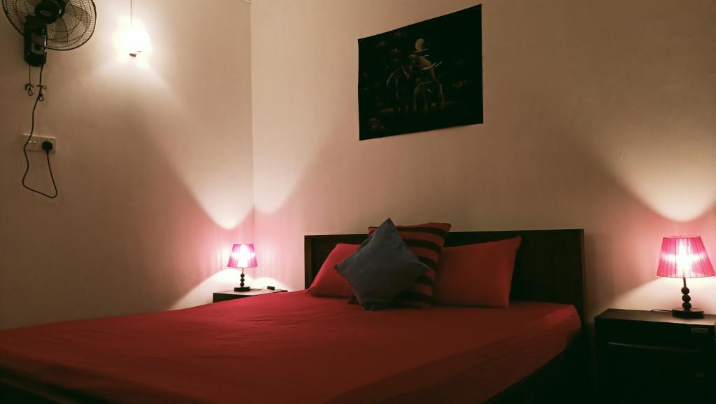 a bedroom with a red bed with two lamps at Dini's home stay in Matara
