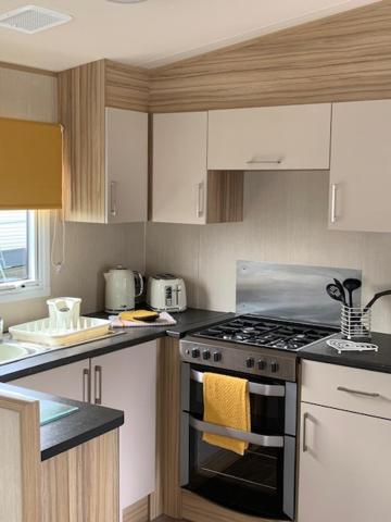 a kitchen with white cabinets and a stove top oven at A 'Small' Hideaway in Pakefield