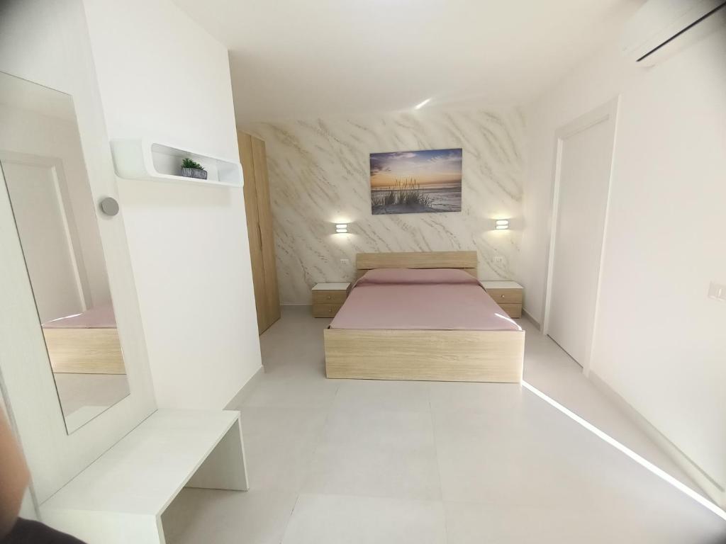 B&B Casa Denittis في بيسكيتشي: غرفة نوم صغيرة مع سرير في غرفة بيضاء