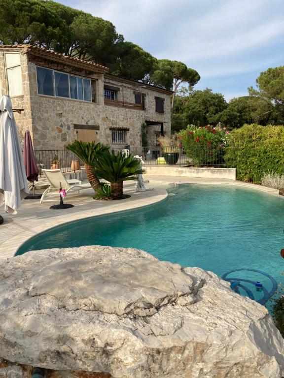 una piscina con una roca frente a una casa en Superbe maison entière villa les pinsons, en Emponse