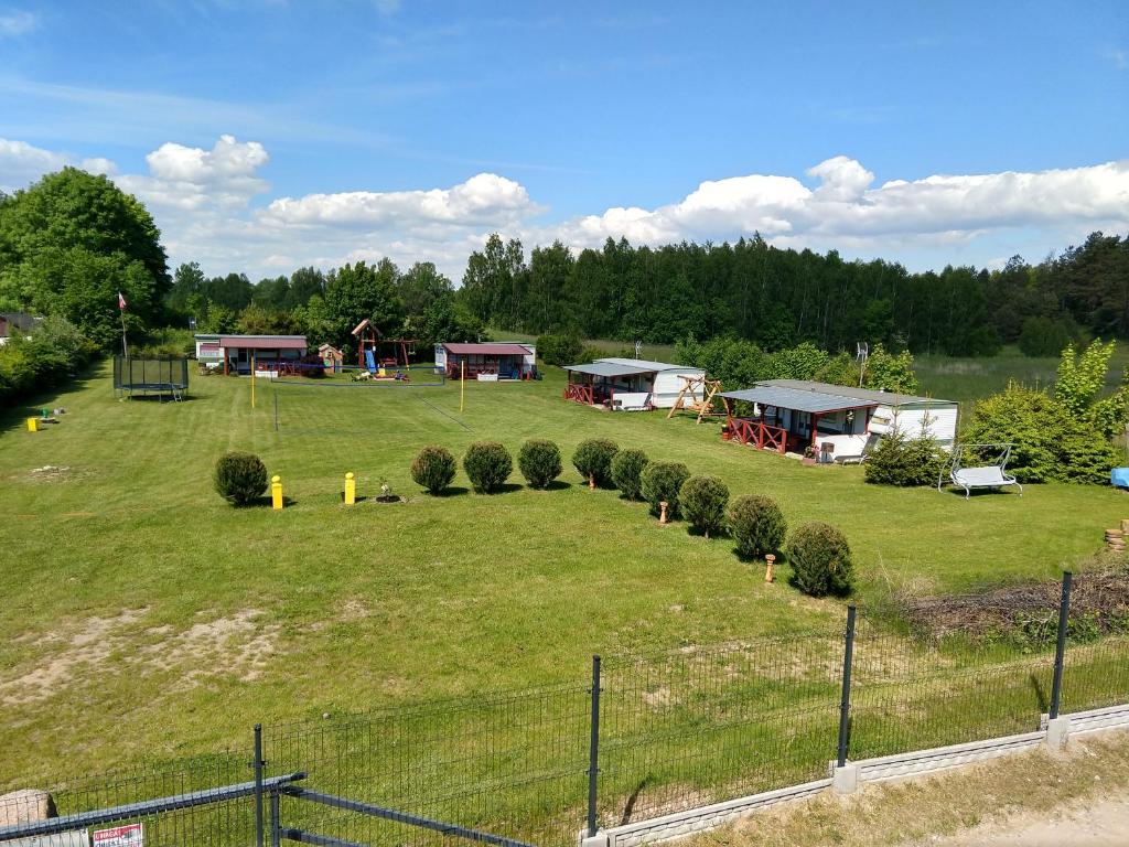 a large grassy field with houses and trees at Domki u Dobrusi in Mikołajki