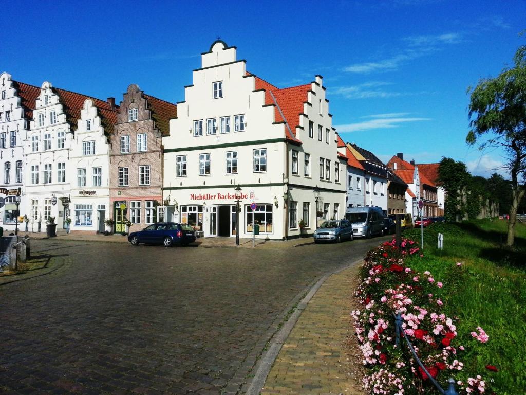 a large white building with cars parked on a street at Pension Marktblick in Friedrichstadt