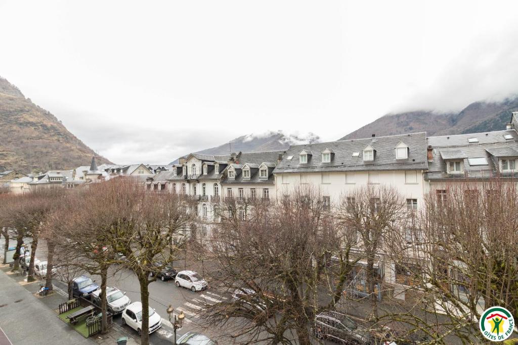 un grand bâtiment avec des voitures garées dans un parking dans l'établissement Appart Luchon au centre des allée d'etigny, à Luchon