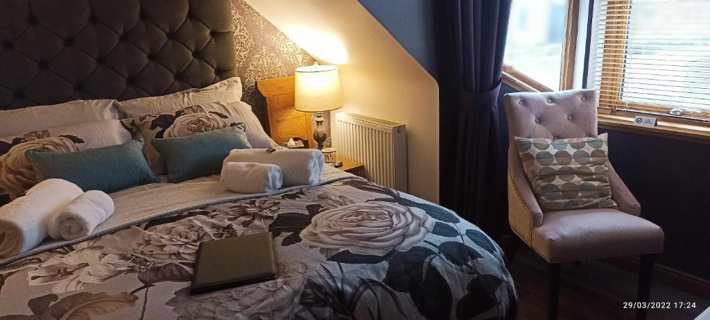 a bedroom with a bed and a chair with a laptop on it at Outlander Boutique B&B King in Cruden Bay