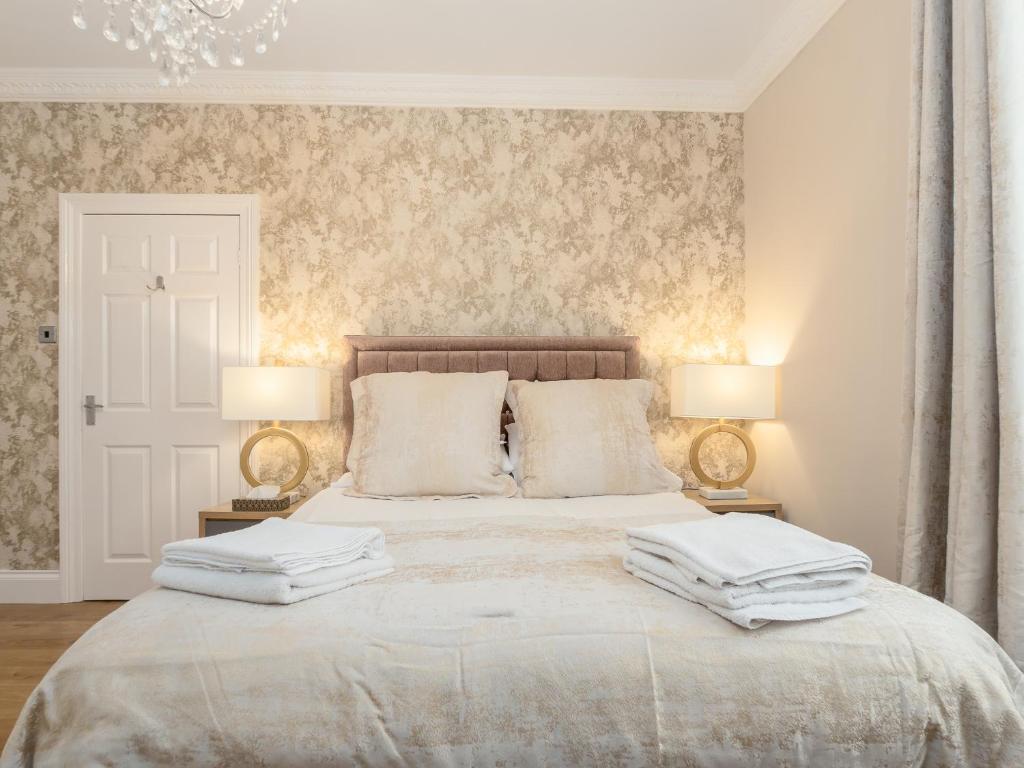 a bedroom with a large white bed with two lamps at Sunderland Self Catering 2 - Violet Cottage Free Parking in Sunderland