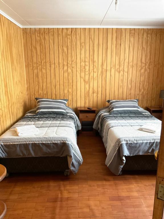 2 letti in una camera con pareti in legno di Hostal Balmaceda a Punta Arenas