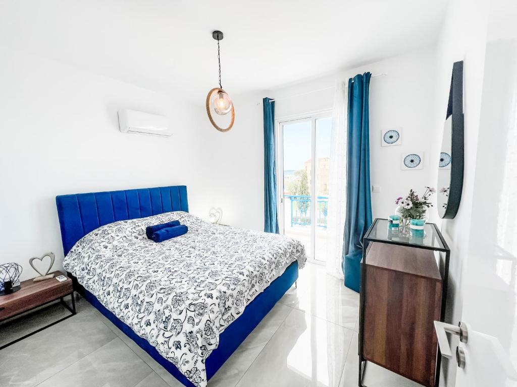 sypialnia z niebiesko-białym łóżkiem i oknem w obiekcie BLUE LATSI w mieście Latsi