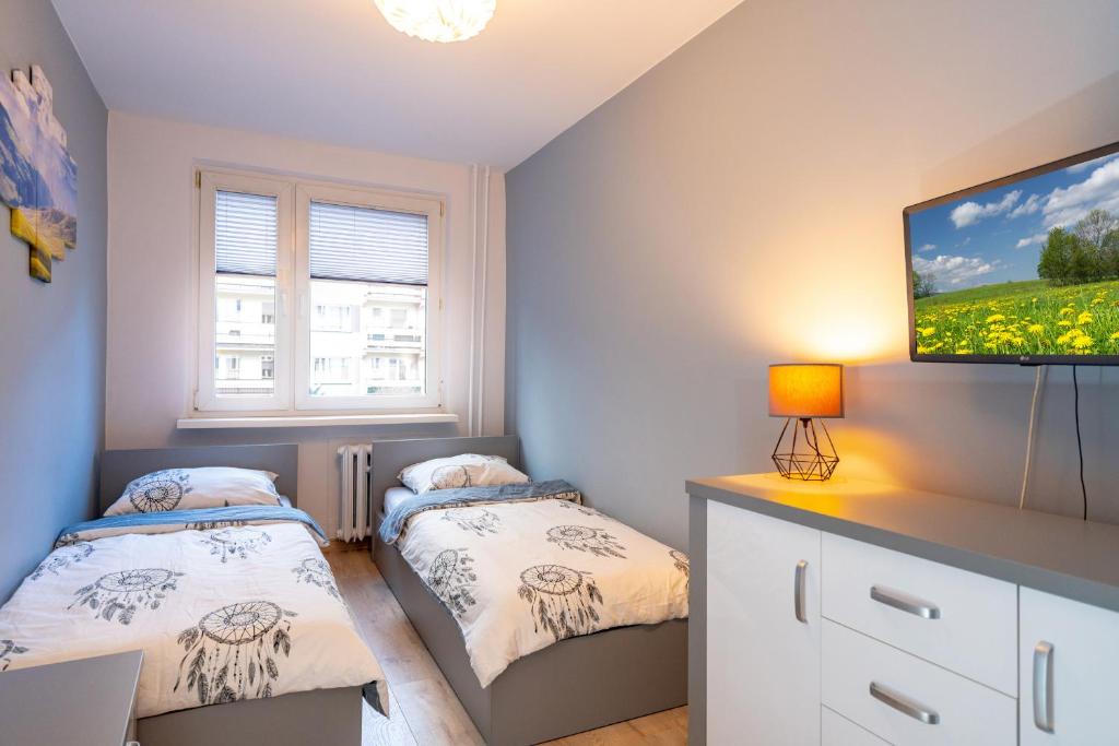Karkonosky Apartamenty - Ismena في شكلارسكا بوريبا: غرفة نوم بها سريرين وتلفزيون بشاشة مسطحة