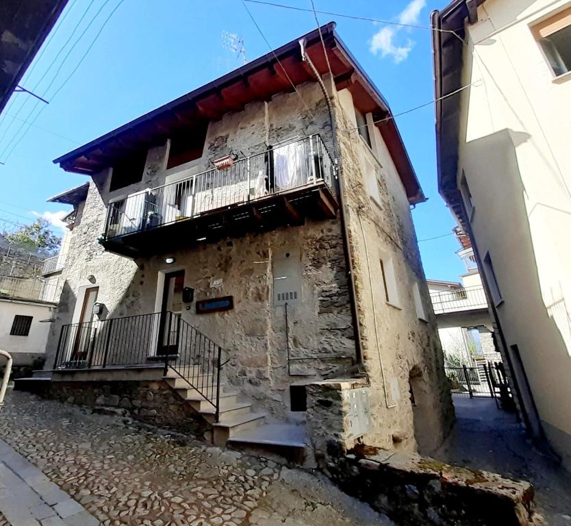 ein altes Steingebäude mit Balkon auf einer Straße in der Unterkunft IL RUSTICO appartamento vacanze in Tresivio