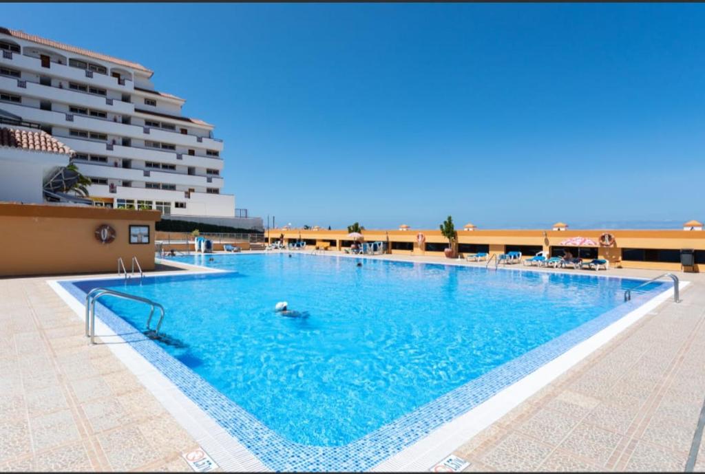 a large swimming pool next to a large building at Apartamento ohana in Puerto de Santiago