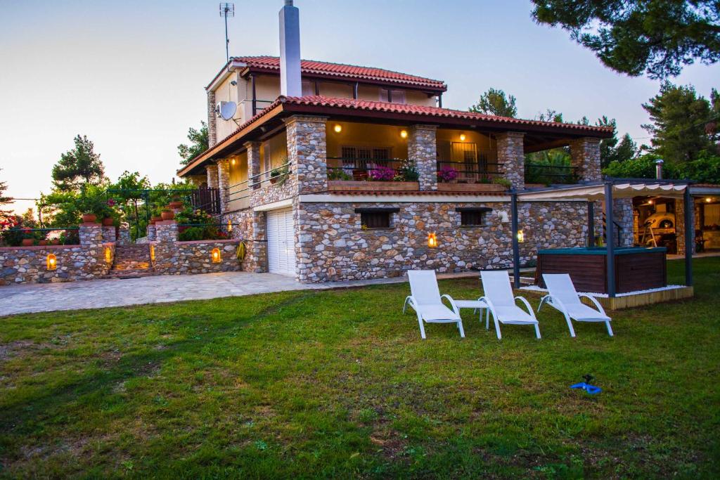 ein Haus mit weißen Stühlen davor in der Unterkunft VILLA GEM in Skiathos-Stadt