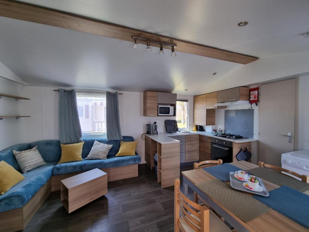 a living room with a blue couch and a kitchen at Camping 4* 3 CH 2 SDB- Lave linge- Lave vaisselle in Onzain