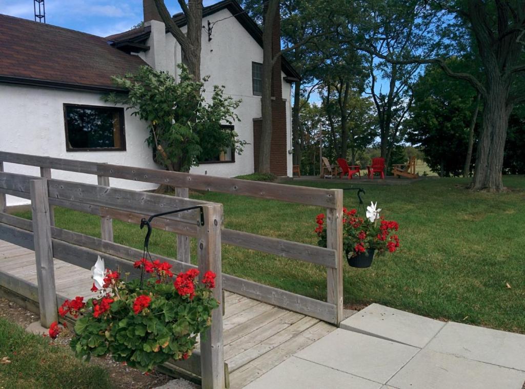 een houten hek met rode bloemen en een huis bij Farmhouse PEC in Hillier