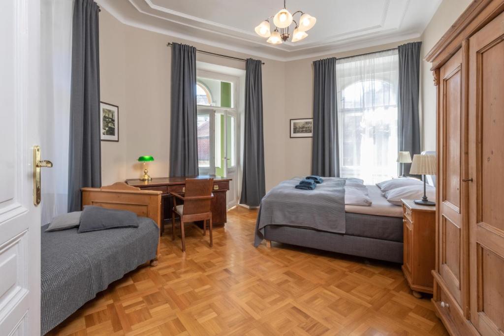 a bedroom with two beds and a desk and a table at Liliova Apartments in Prague