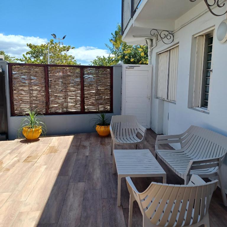 une terrasse avec deux bancs, une table et des chaises dans l'établissement Maison de vacances les pieds dans l'eau, à Schœlcher