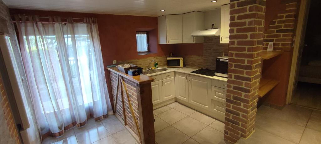 a kitchen with white cabinets and a brick wall at La maison du pêcheur in Livinhac-le-Haut