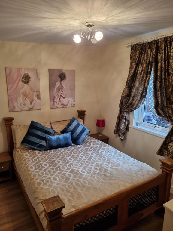 um quarto com uma cama com almofadas azuis e uma janela em Nanny's little highland hoose em Inverness