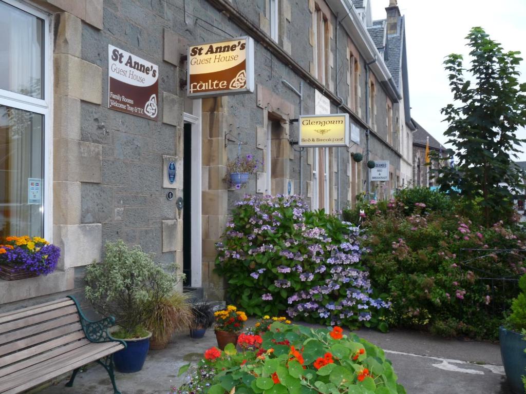 a building with flowers and a bench in front of it at St Annes Guest House in Oban