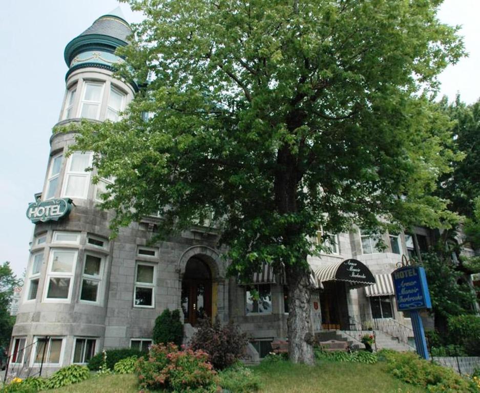 un grand bâtiment avec un arbre en face dans l'établissement Manoir Sherbrooke, à Montréal