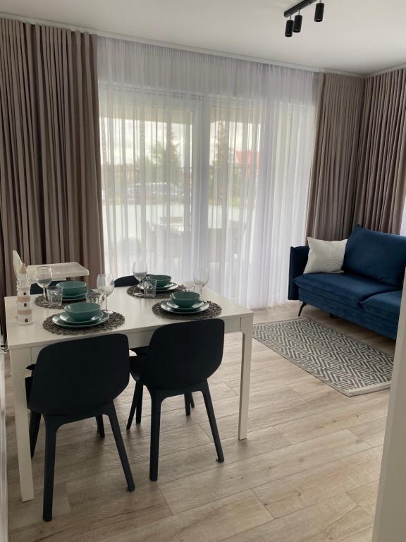 salon ze stołem z krzesłami i niebieską kanapą w obiekcie Apartament BLUE Rewal w Rewalu