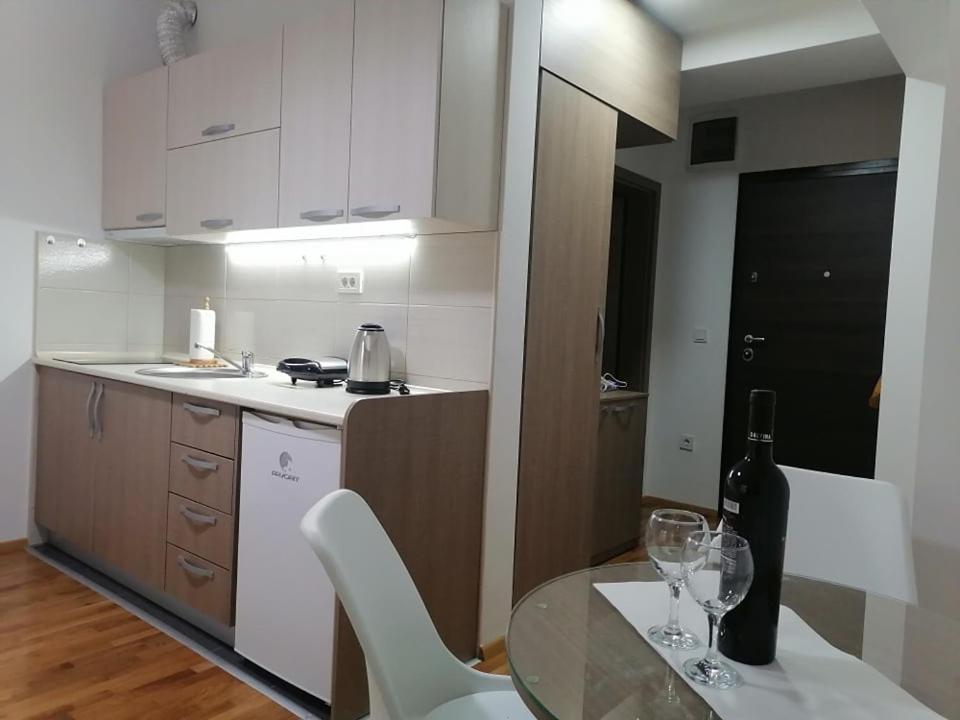 una cucina con tavolo in vetro e una bottiglia di vino di Cosmopolit Apartments a Ohrid