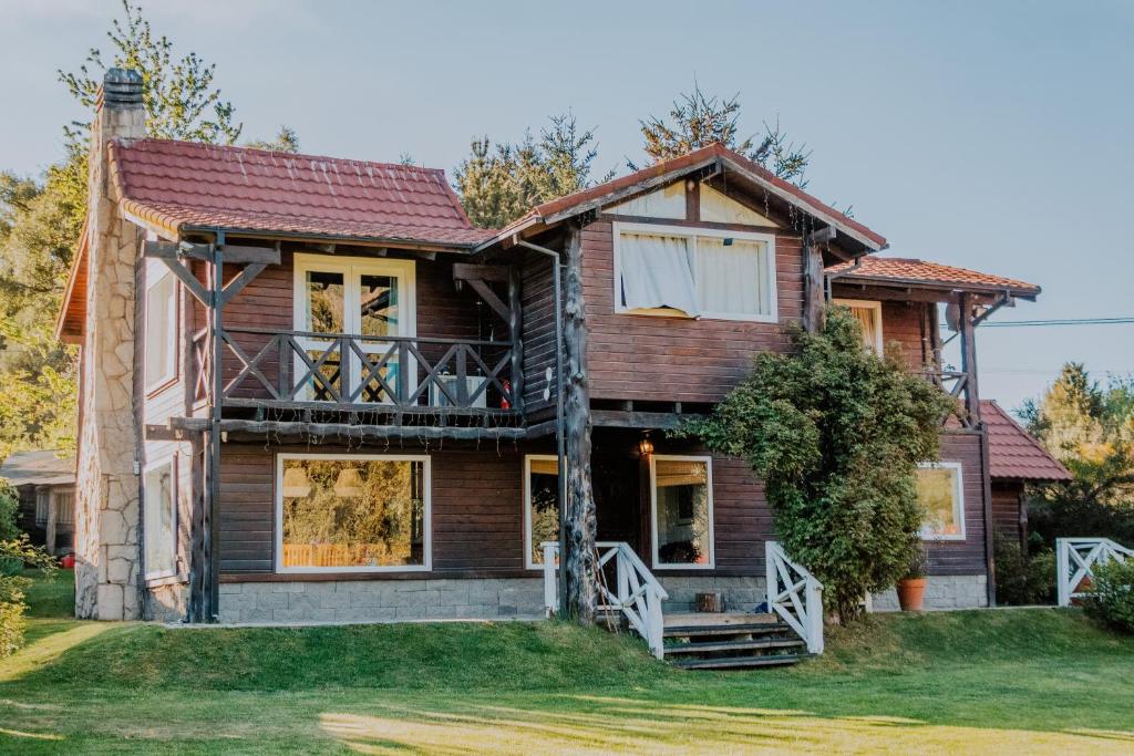 a log house with a porch and a balcony at INDÓMITO HOSTEL in San Carlos de Bariloche