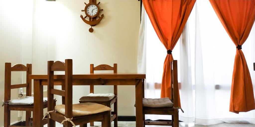 une table à manger avec des chaises et une horloge murale dans l'établissement Amanecer del Fuego I, à Ushuaia