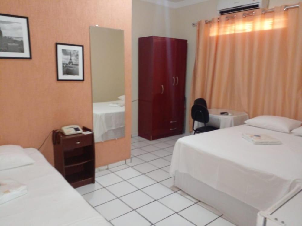 Habitación de hotel con 2 camas y espejo en Pousada Terra do Sol en Caicó