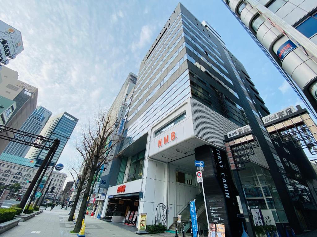 um edifício alto numa rua da cidade com em First Cabin Midosuji Namba em Osaka