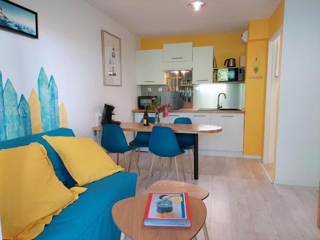 a living room with a blue couch and a kitchen at Pretty apartment with a terrace near a sandy beach in Saint-Nic