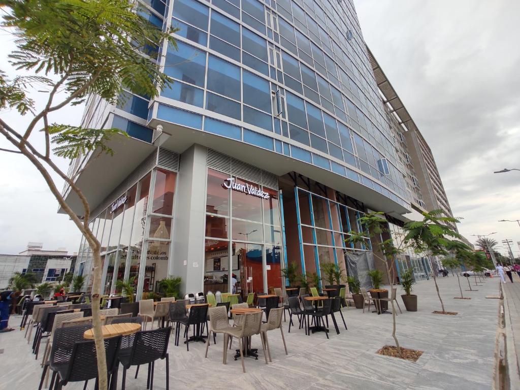 a building with tables and chairs in front of it at Distrito 90 - Estudios y Apartamentos para vacaciones y viajes de negocio in Barranquilla