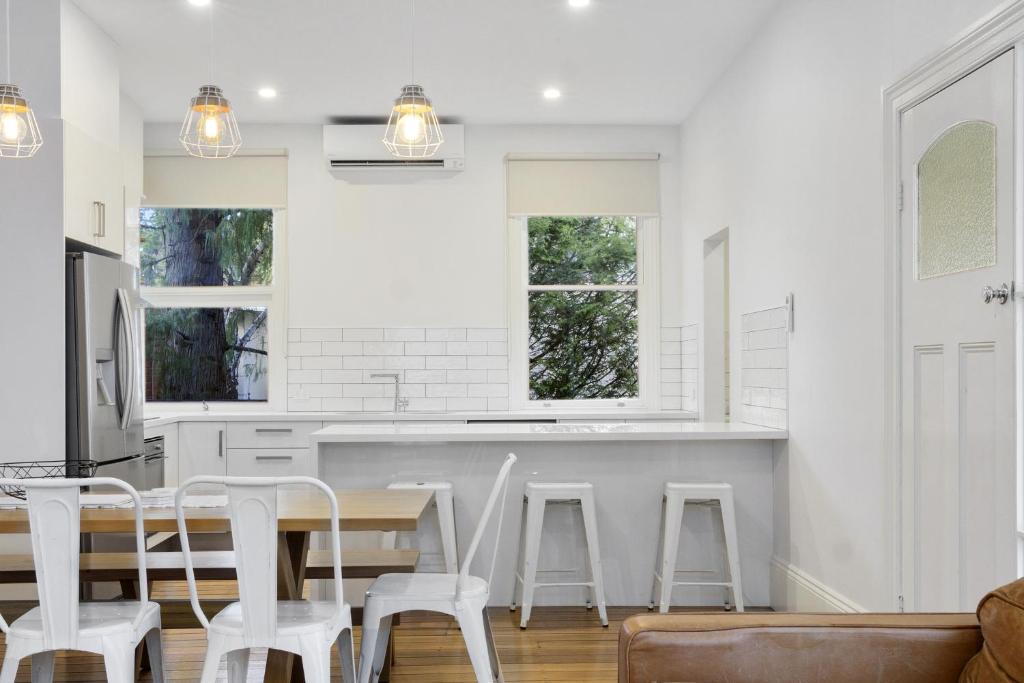 a kitchen with white walls and white stools at House on Grosvenor in Sandy Bay