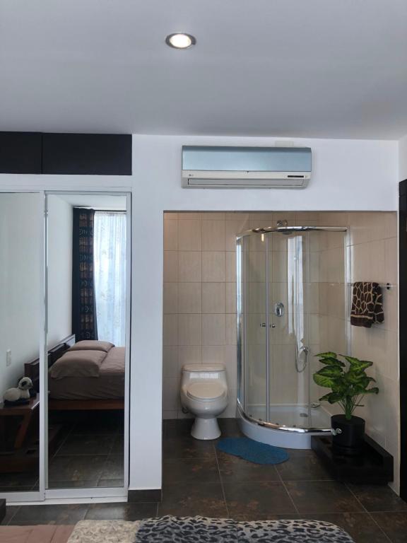 a bathroom with a shower and a toilet and a bed at Punta Centinela Apartment in Punta Blanca