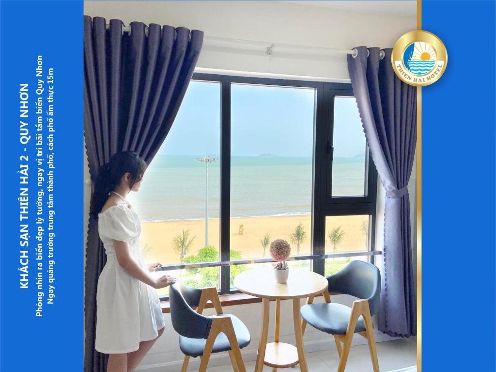 a woman standing in front of a window with a table and chairs at Thiên Hải 2 Hotel in Quy Nhon