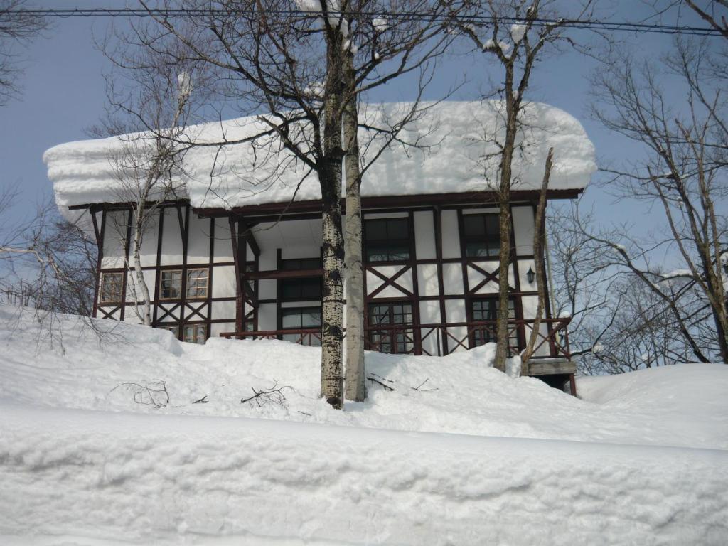 a house covered in snow in front at Chalet Myoko in Myoko