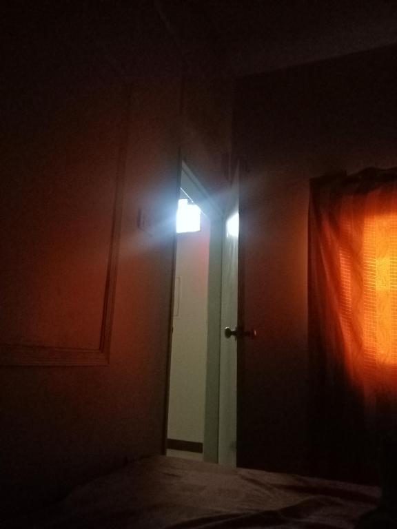 a dark room with a door with a light on it at White Rose Guest House Karachi in Karachi