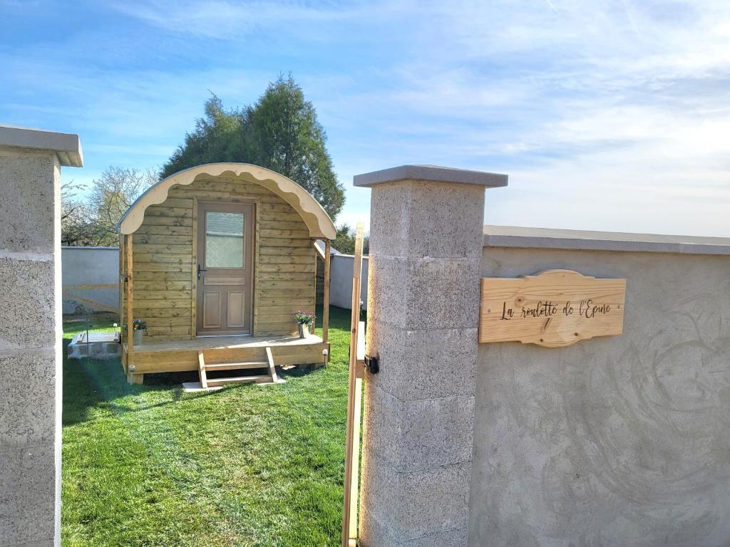 ein kleines Holzhaus mit einem Schild an der Wand in der Unterkunft Gîte de la Roulotte de l'Epine in Dallon