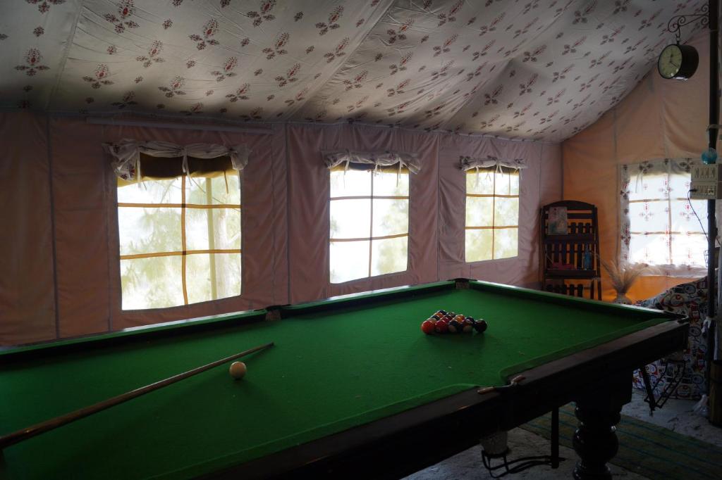 una mesa de billar verde en una habitación con ventanas en Jaseelo Camps, en Chamba