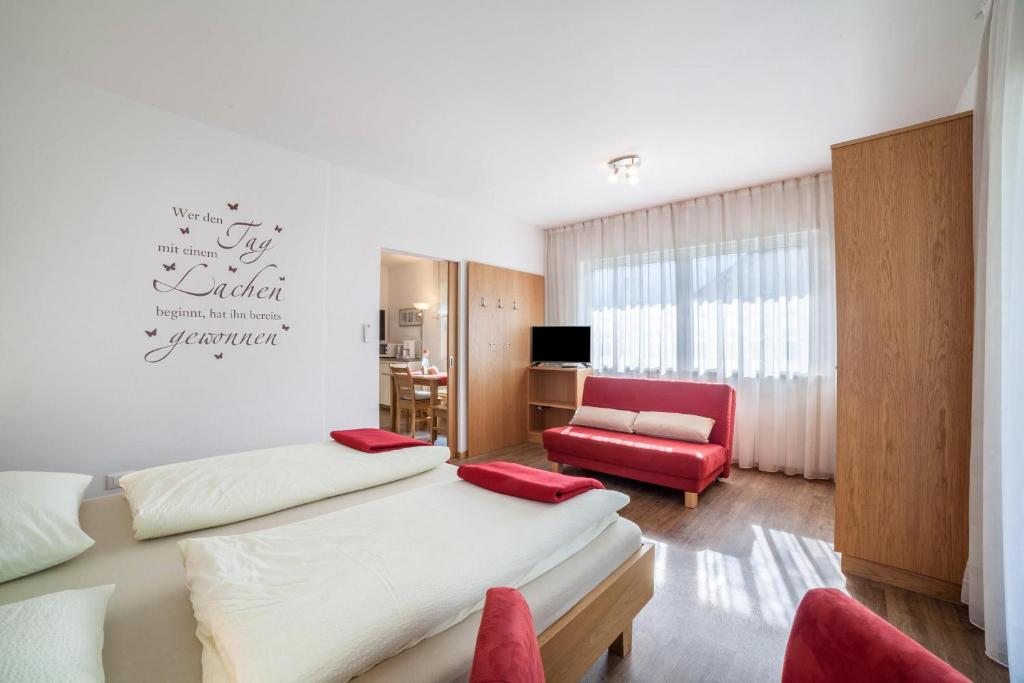Pokój hotelowy z 2 łóżkami i czerwonym krzesłem w obiekcie Schnitzer Ferienwohnung Hagebutte w mieście Rablà