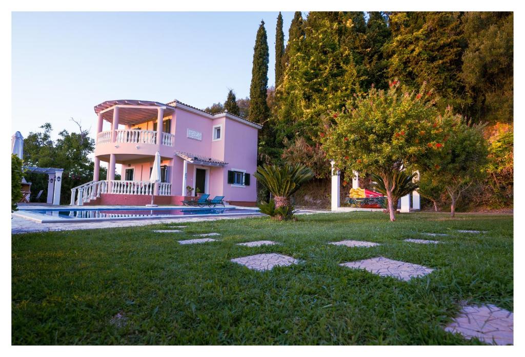 a pink house with a lawn in front of it at Private Villa's in NW Corfu with Pool in Kavvadádes