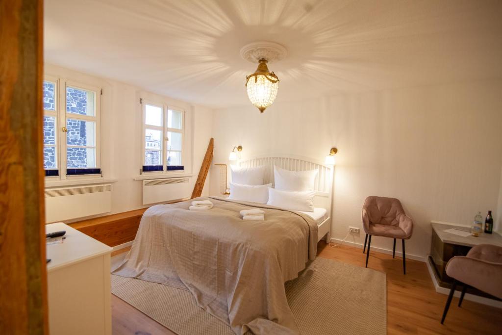 a bedroom with a bed and a chair and windows at ApartOne Palais-Apartments in Bautzen