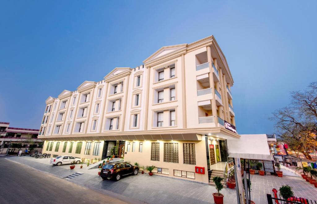 ein weißes Gebäude mit davor geparkt in der Unterkunft Hotel Yash Regency in Jaipur