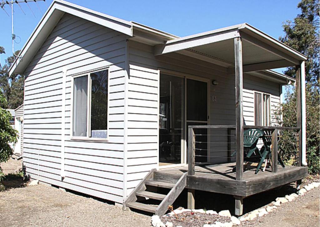 Casa blanca pequeña con porche y silla en Kangaroo Island Coastal Villas, en American River