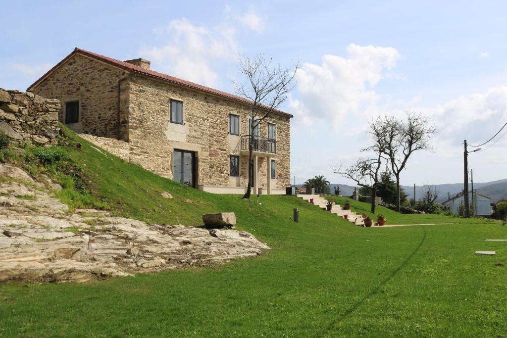 una casa de piedra en la cima de una colina con césped en O lar de san fins, en A Coruña