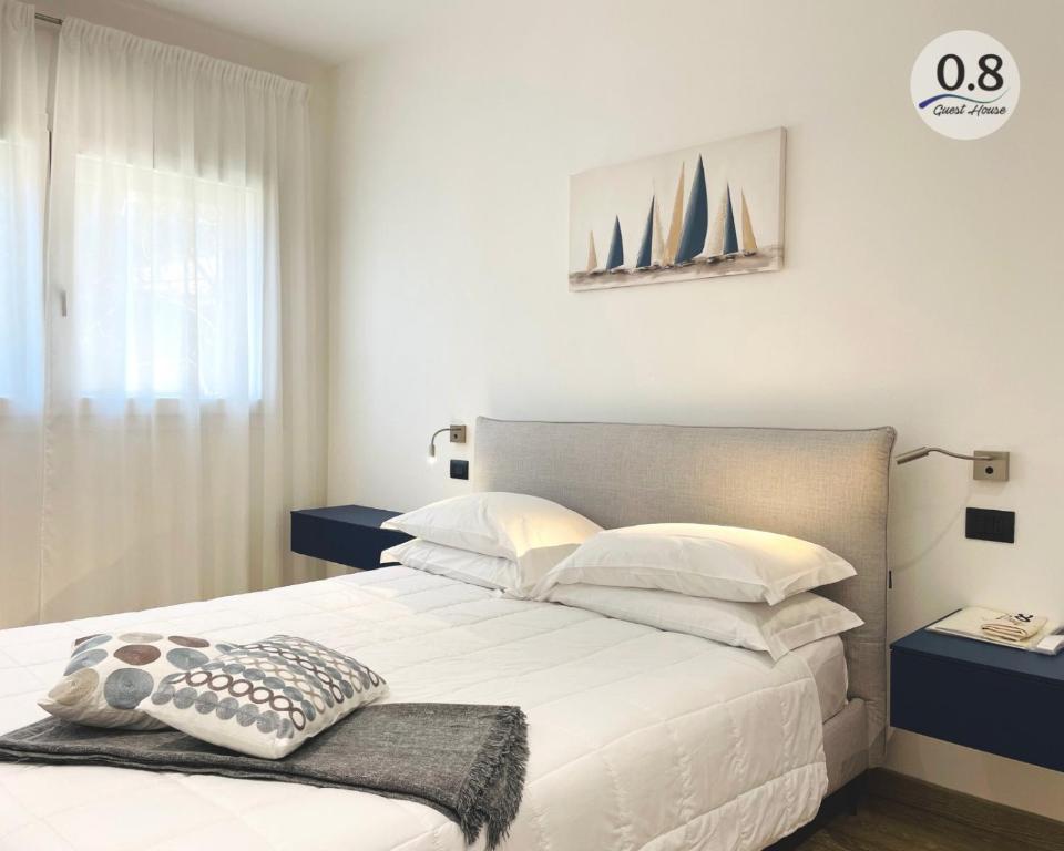 1 dormitorio con 1 cama con sábanas y almohadas blancas en 0.8 Guest House, en Porto Ercole