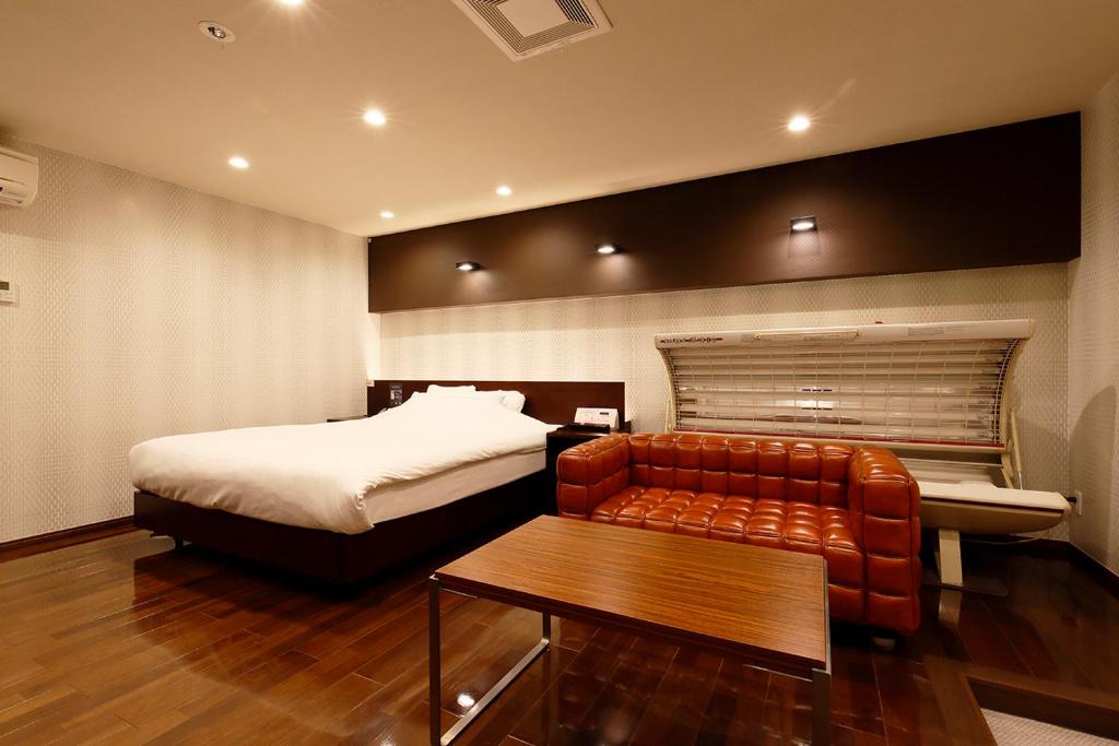 a bedroom with a bed and a couch and a table at HOTEL 555 Air in Higashine