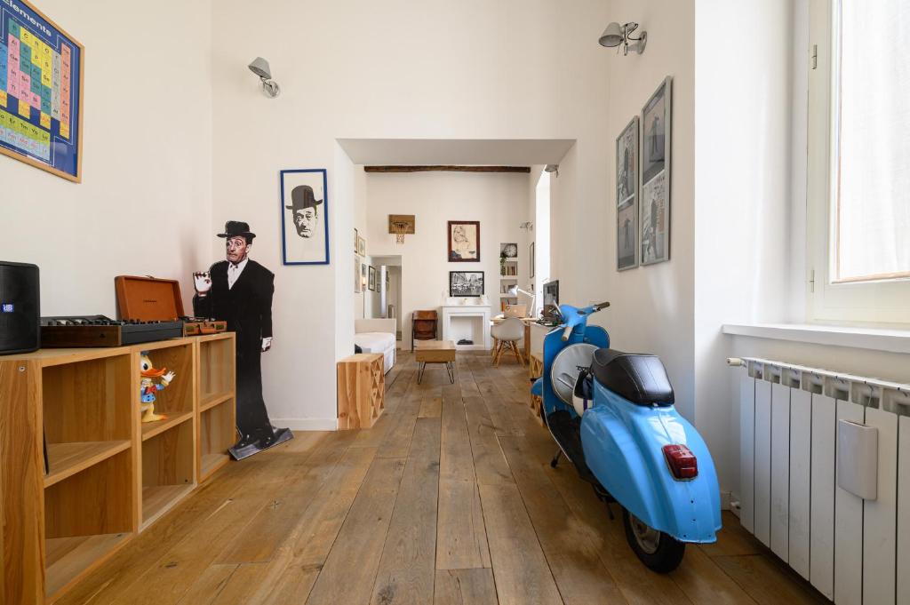 a man standing in a room with a blue scooter at Vespa Apartment in Naples