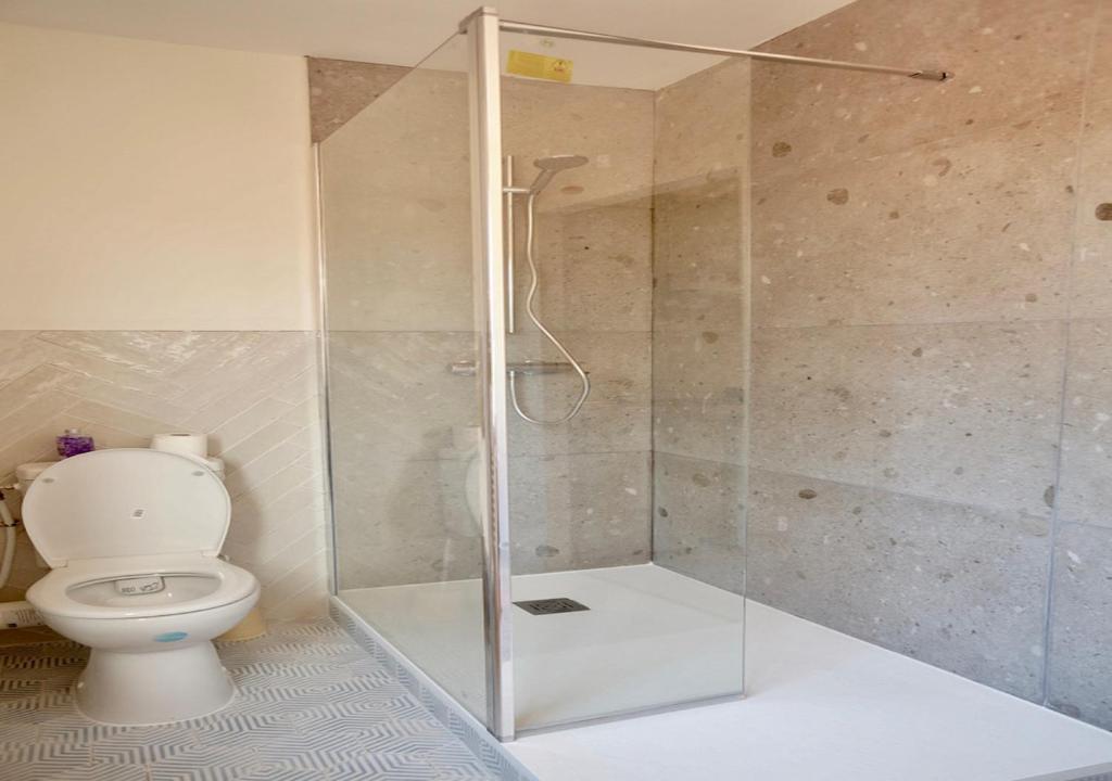 a bathroom with a glass shower with a toilet at Hotel et Studios Le Marina Baie de La Baule in Pornichet