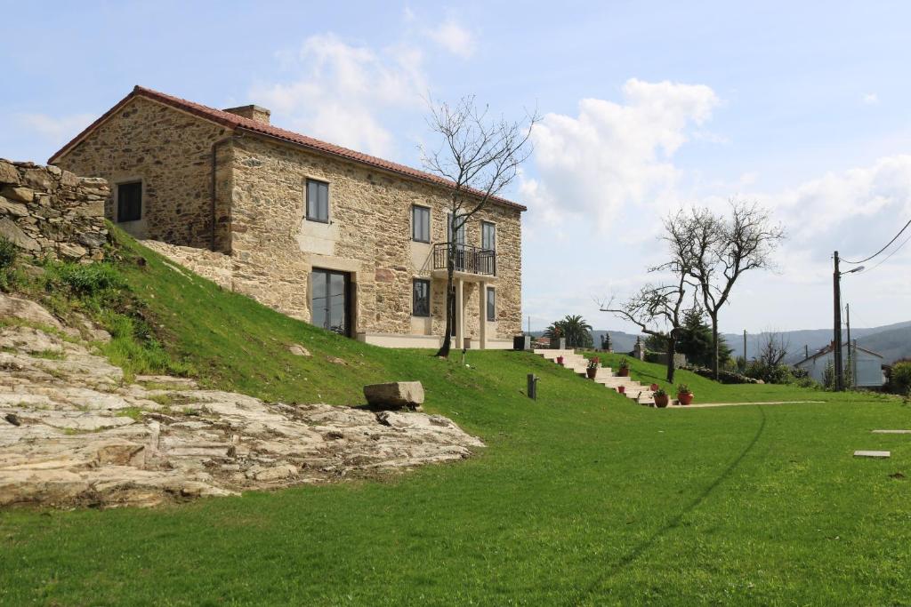 una casa de piedra en la cima de una colina con césped en O lar de San Fins-Casita rural, en A Coruña