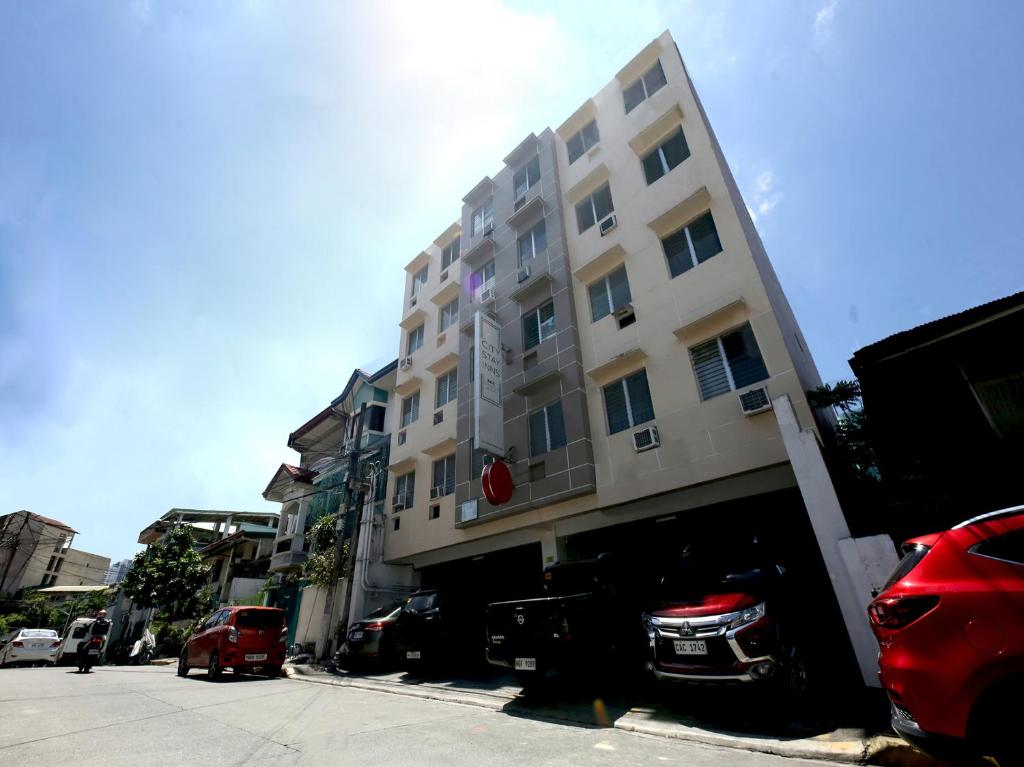 wysoki budynek z samochodami zaparkowanymi przed nim w obiekcie OYO 858 City Stay Inns Bgc Nuevo w mieście Manila